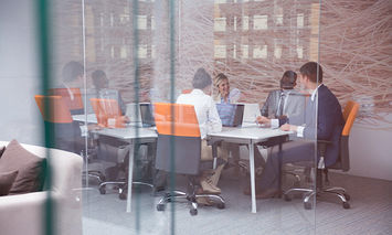 A group of office workers gathered at a conference table in an office setting.